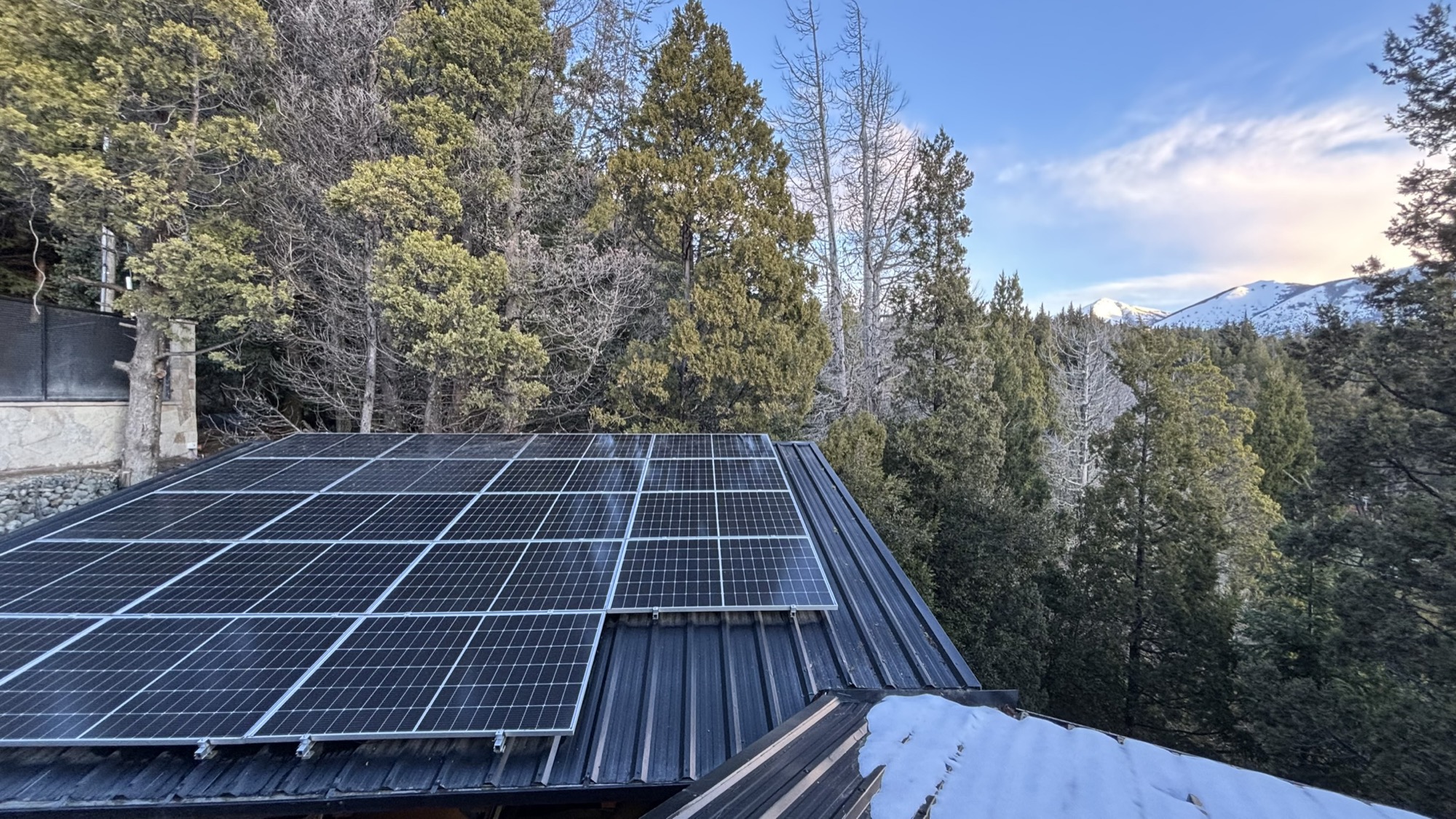 Paneles solares en el techo, con el bosque y la cordillera nevada de fondo