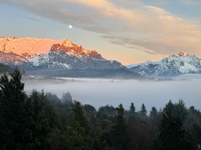 Luna llena sobre la cordillera nevada, con niebla en el valle